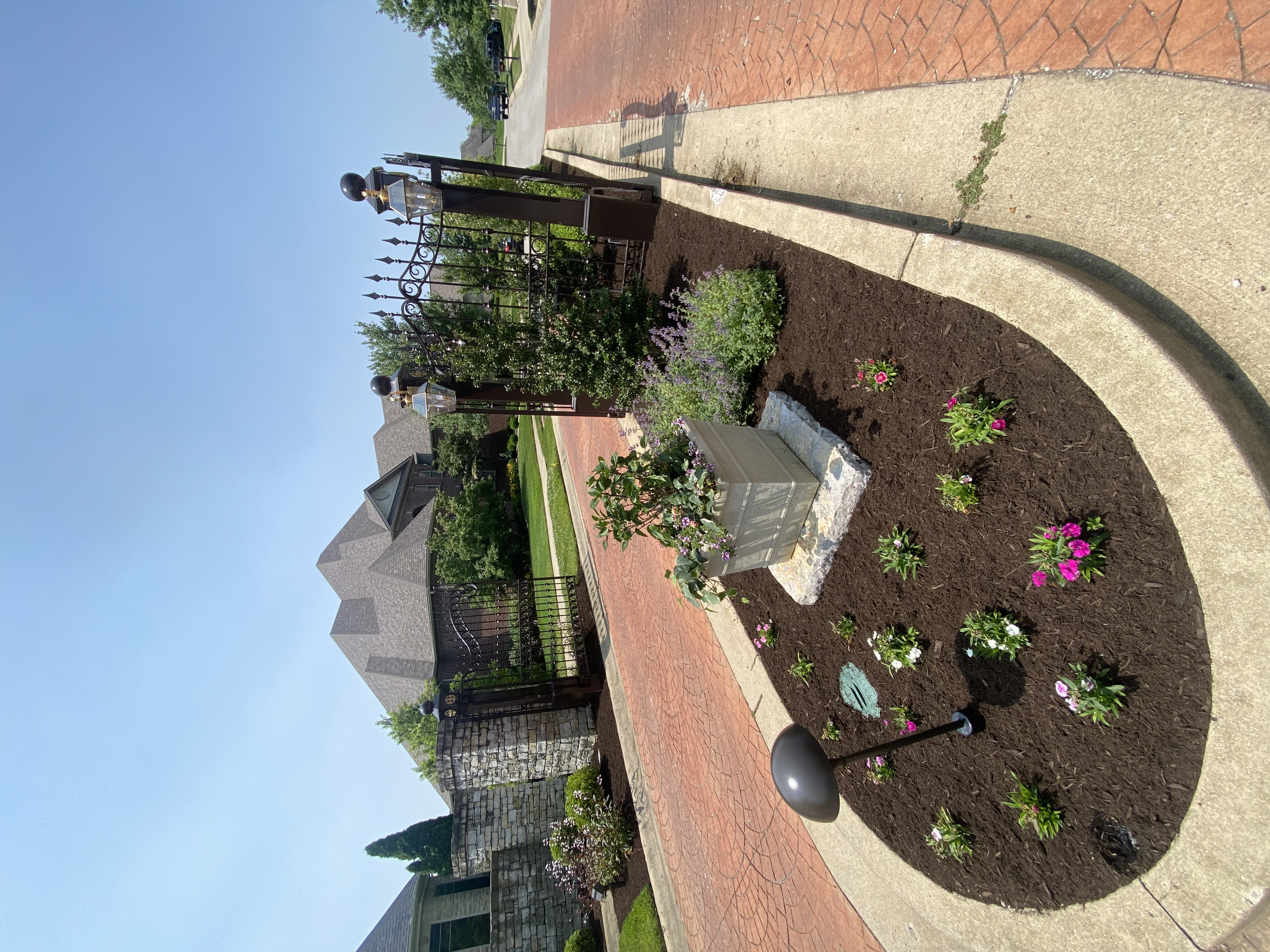 Flower bed with colorful annual plantings along brick walkway